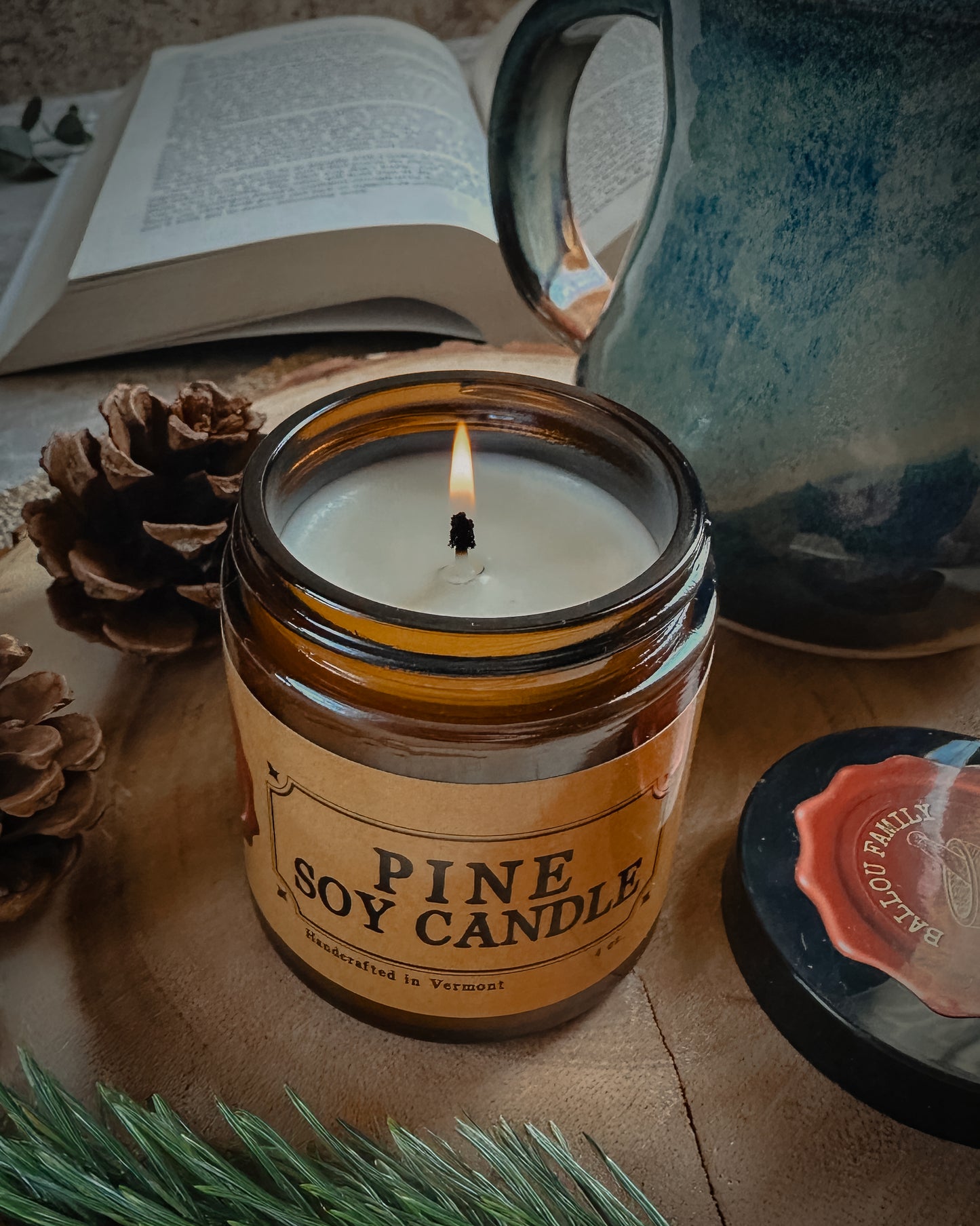 Lit Pine Soy Candle with a mug and book in the background