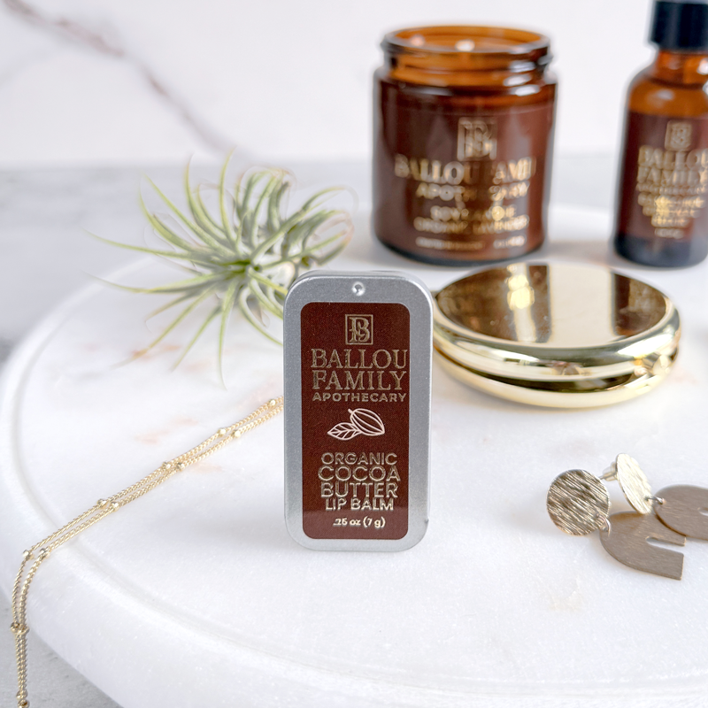 Ballou Family Apothecary lip balm on a white surface with decorative items.