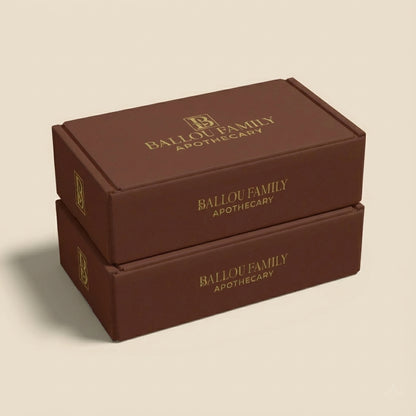 Two gift set boxes with 'Ballou Family Apothecary' branding on a beige background
