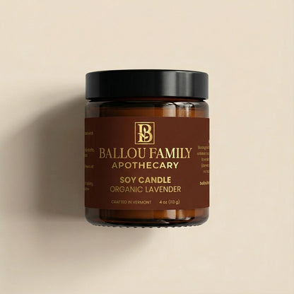 Soy candle jar with Ballou Family Apothecary branding on a beige background