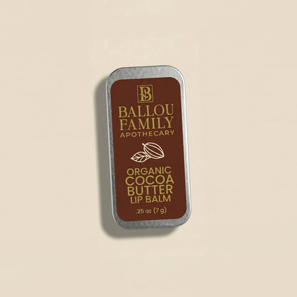 Ballou Family Apothecary organic cocoa butter lip balm tin on a beige background