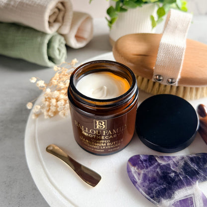 Jar of Ballou Family Apothecary magnesium butter on a white tray with a brush and lavender stone.