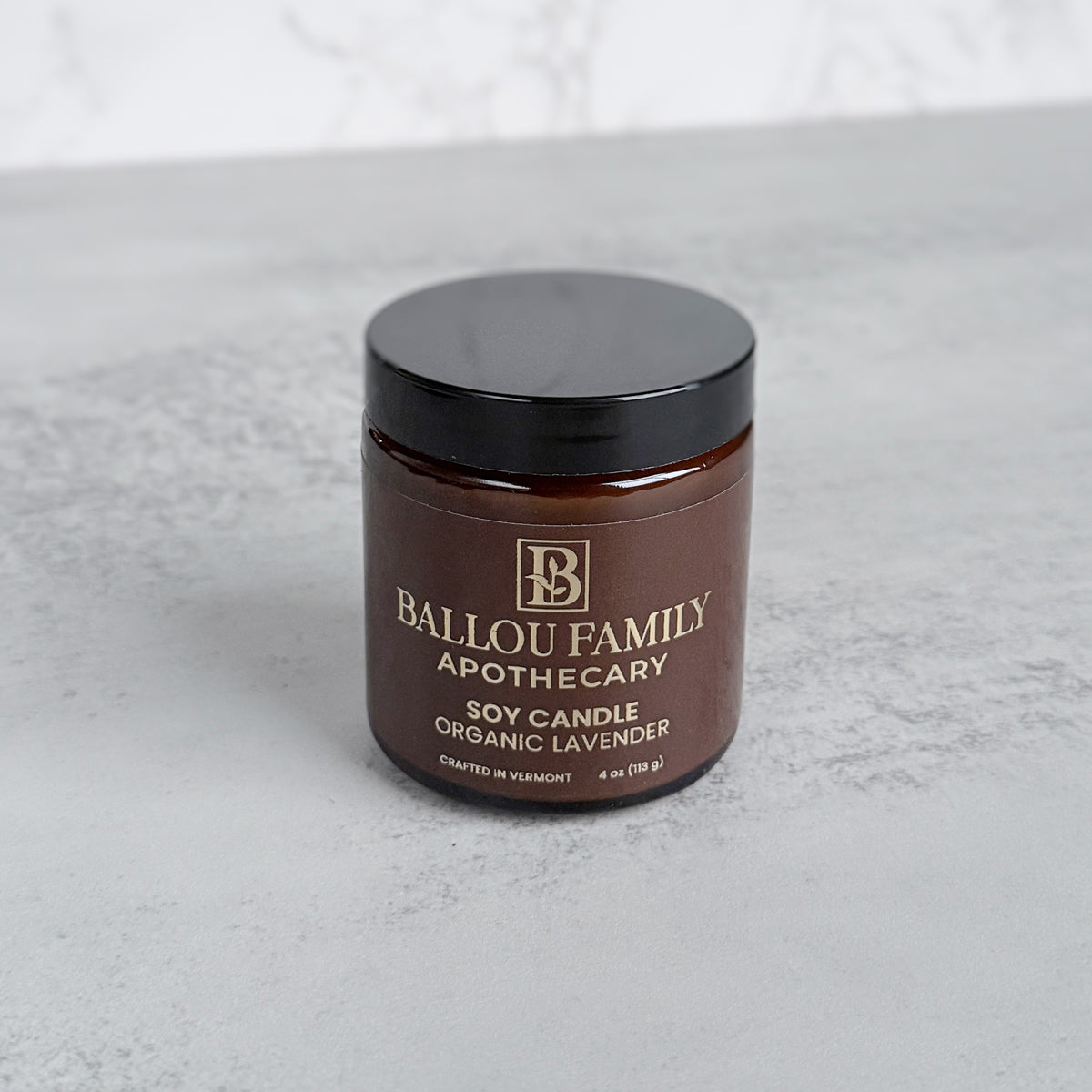 Brown Candle jar with black lid labeled 'Ballou Family Apothecary' on a light gray background