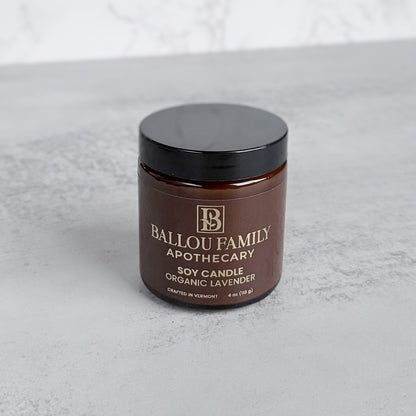 Brown Candle jar with black lid labeled 'Ballou Family Apothecary' on a light gray background