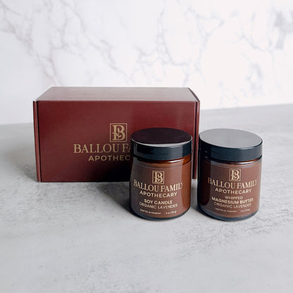 One jar of Ballou Family Apothecary Magnesium Butter and one Soy Candle with a branded box on a light background