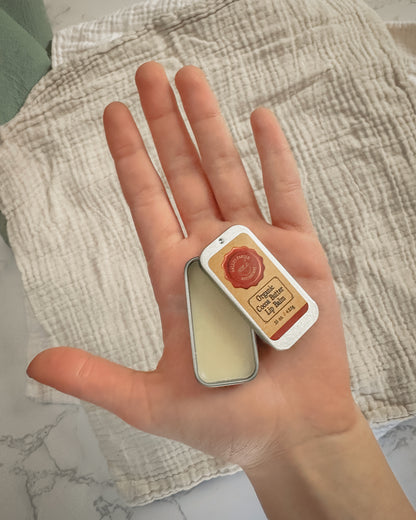 Tin of Organic Cocoa Butter Lip Balm in a an open hand