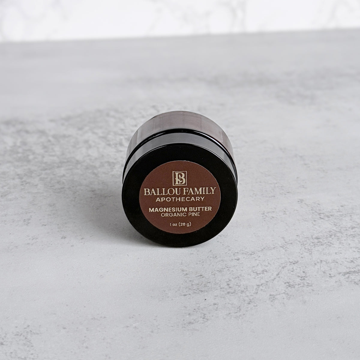 Small jar of Ballou Family Apothecary magnesium butter on a gray surface