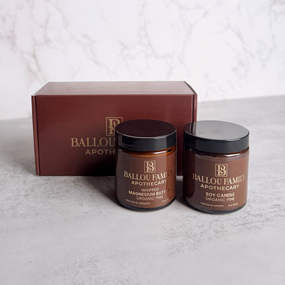 One jar of Ballou Family Apothecary Magnesium Butter and one Soy Candle with a branded box on a light background