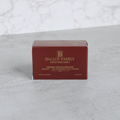 Box of pine scented soap with 'Ballou Family Apothecary' branding on a gray surface.