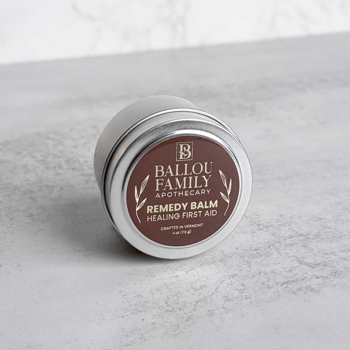 4 oz Ballou Family Apothecary Remedy Balm tin on a gray surface