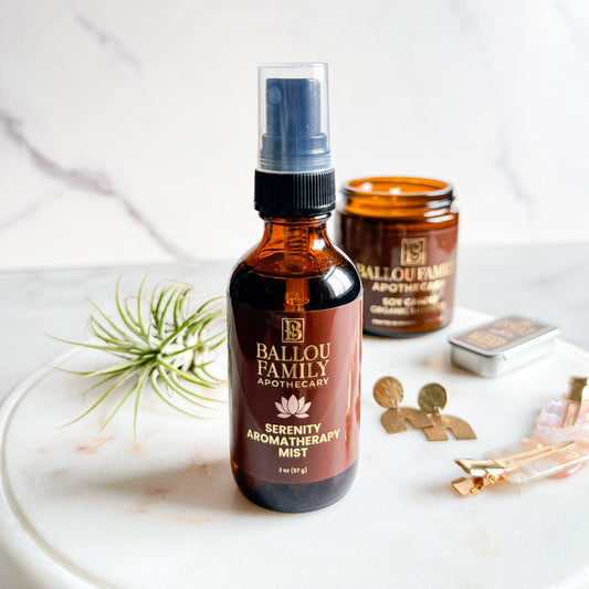 Ballou Family Apothecary Serenity Aromatherapy Mist bottle on a white surface with a jar and decorative items.