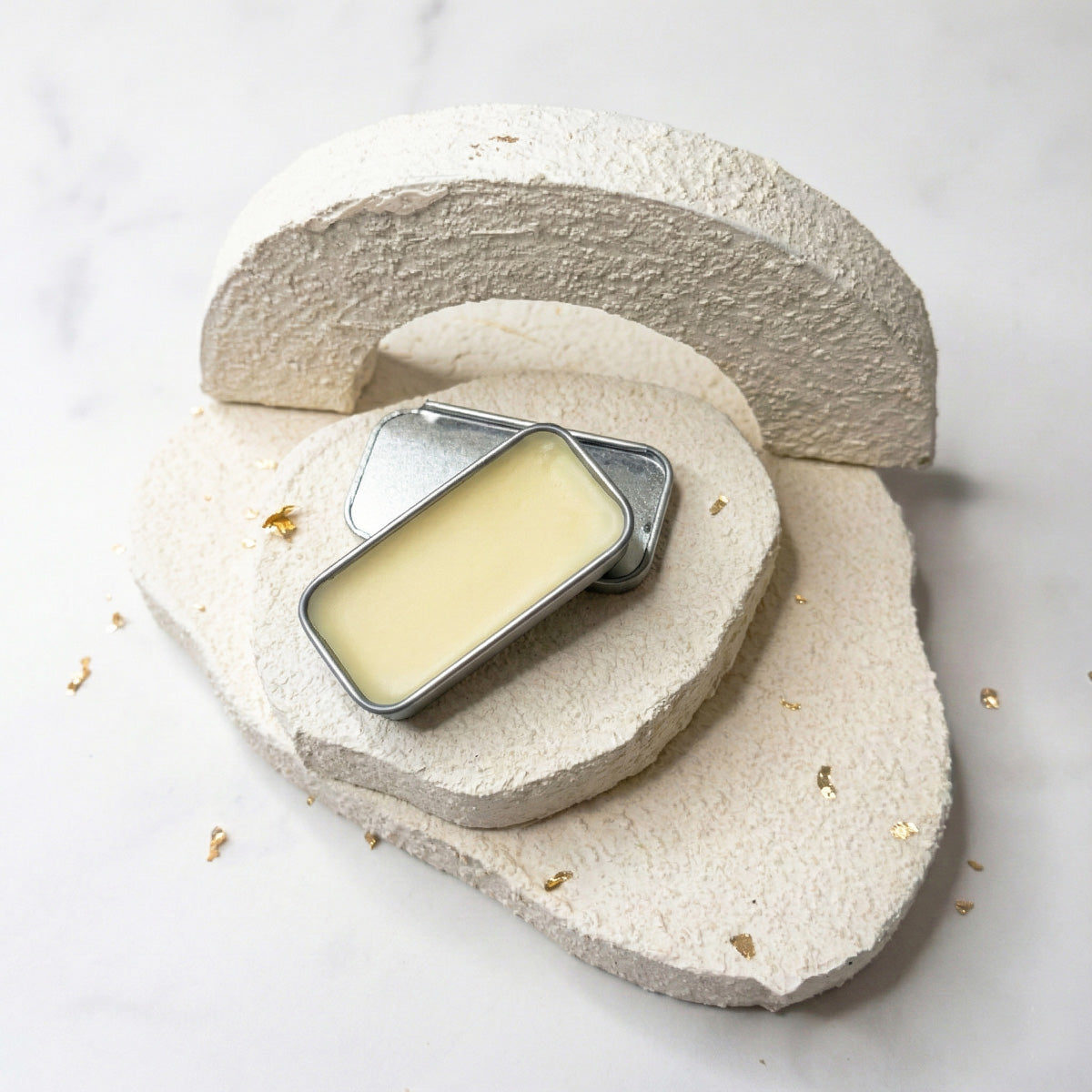 Oragnic lip balm in a vintage tin container on a stone surface